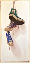 vintage colored converse sneakers in green, purple, and blue hanging by laces in front of off-white background