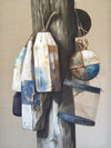 Contemporary, nautical, oil painting by Michel Brosseau of assorted buoys hanging on a beach post