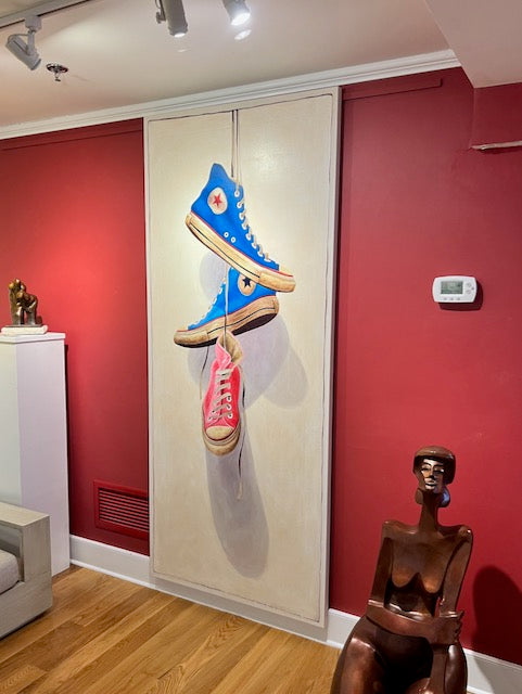 oil painting of dark blue, light blue, and pink high top converse sneakers hanging by laces on off white canvas