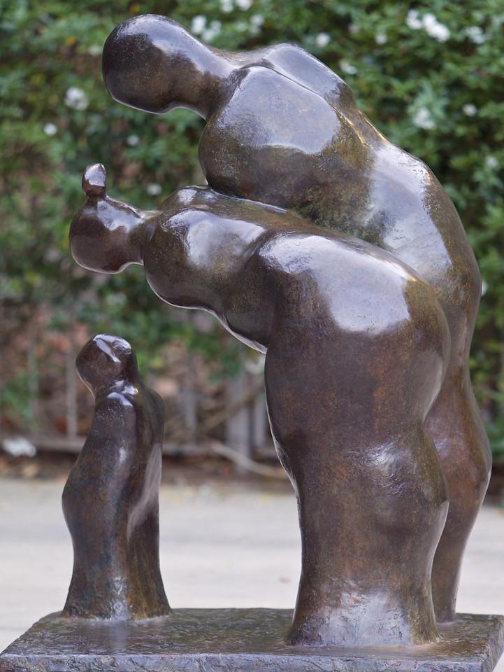 Contemporary life size bronze figurative sculpture of parents bending over a child