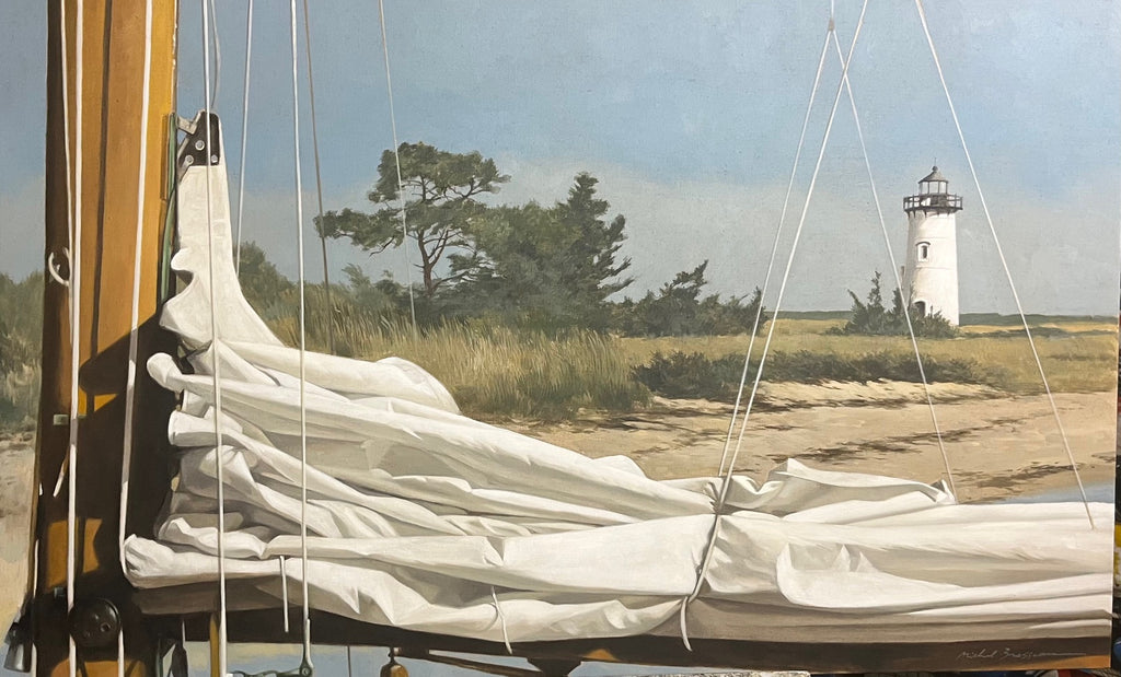 A folded sail rests in the foreground of edgartown lighthouse