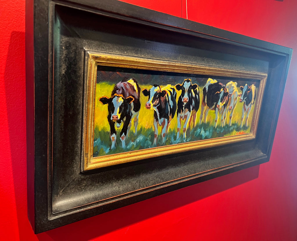 Horizontal oil painting of black and white cows in a row
