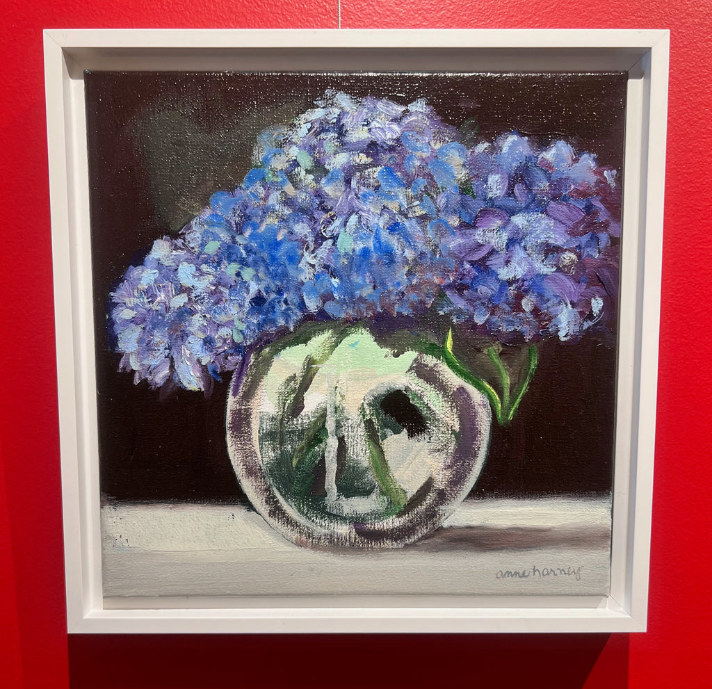 small scale oil painting of blue flowers in a clear vase with black background