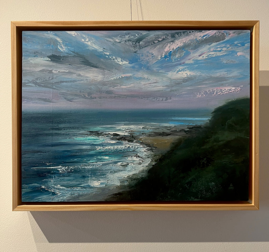 Oil painting by Whitney Knapp of the ocean shoreline by cliffs with a pastel pink and blue sky
