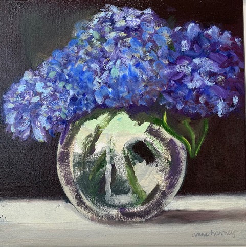 small scale oil painting of blue flowers in a clear vase with black background