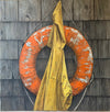 Nautical, still life, oil painting of worn down orange life buoy and a yellow rainjacket hanging on a dark shingled building wall