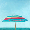 small scale oil painting of pink, yellow and turquoise beach umbrella with blue sky and ocean behind 