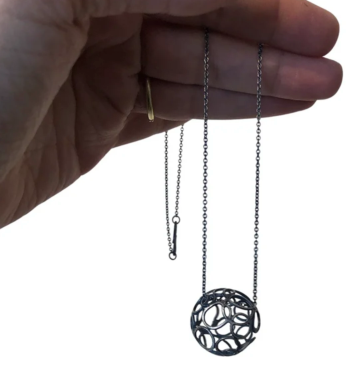 Oxidized sterling silver soldered circles make ball. 1" in diameter suspended on 18" cable chain with handmade clasp.