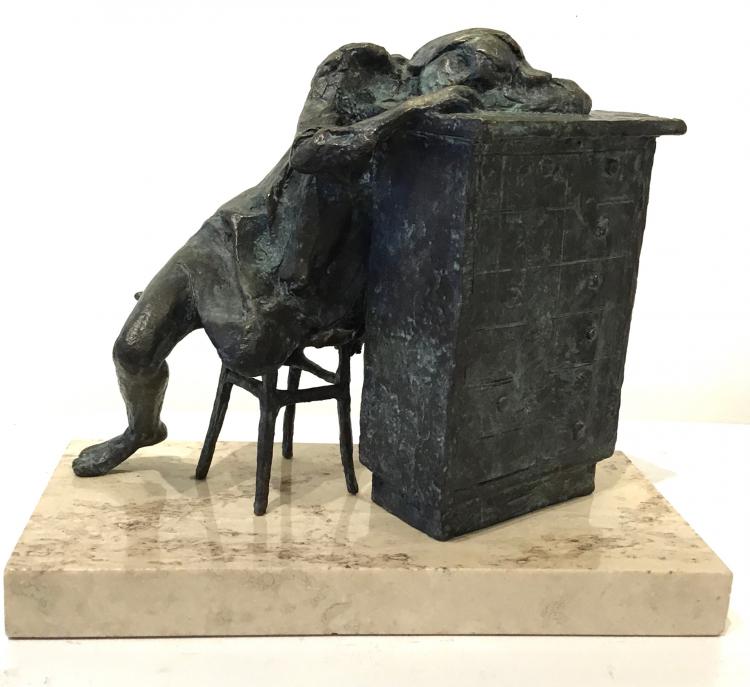 Figure bronze sculpture of a girl sitting in a chair resting her arms and head on a desk
