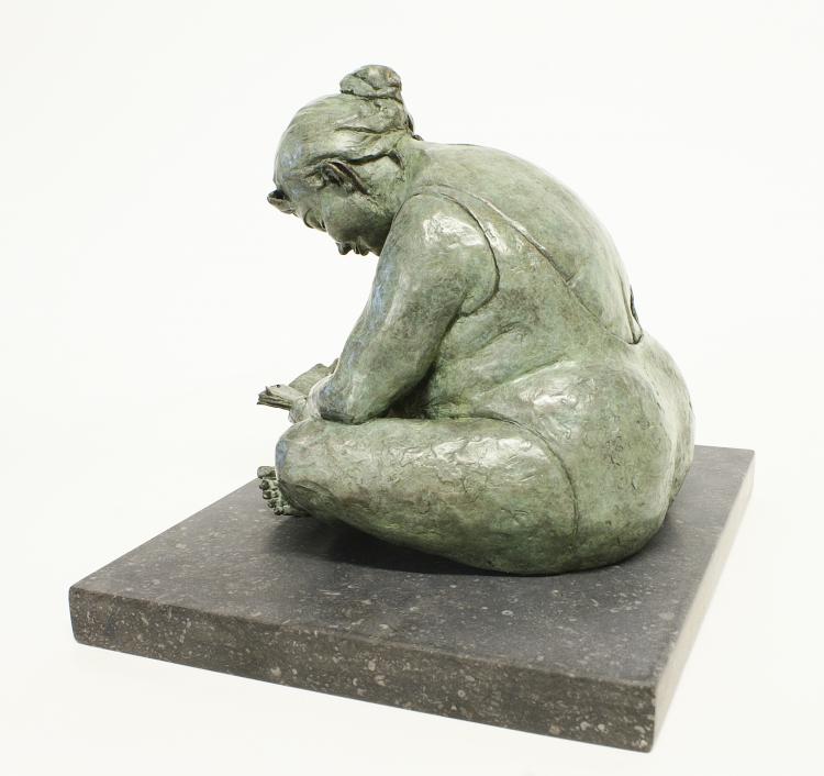 bronze sculpture of a plus-sized woman sitting cross-legged reading a book